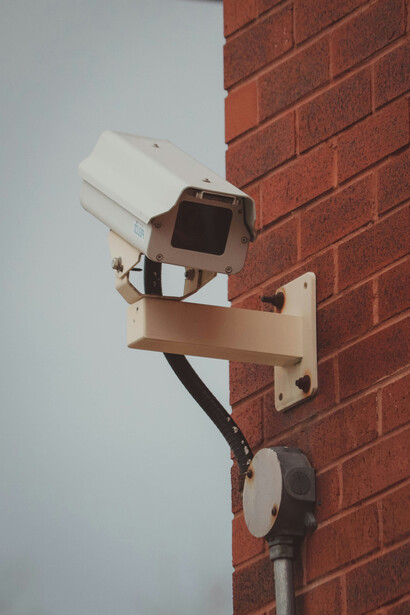 A security camera fixed to a brick wall highlights the critical relationship between surveillance technology and the ongoing debates surrounding data privacy
