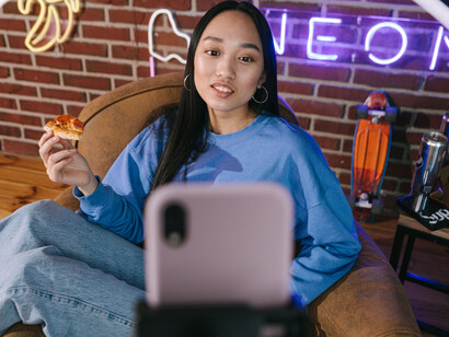 A young Asian influencer streams live indoors, using colorful neon lighting to create an immersive experience for her online audience