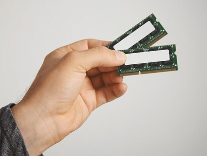Man in a dark grey long-sleeve shirt holding an unlabelled memory chip, isolated on a white background, close-up