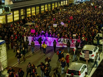 Crowds of demonstrators march through a busy city street during a vibrant nighttime protest in Rome, Italy