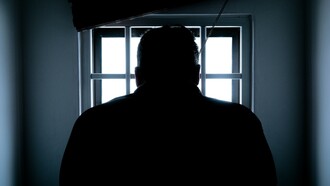 A person sat alone looking towards a window