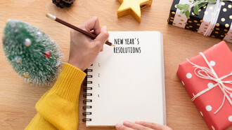 Woman hand writing New years resolution on note paper on new year day