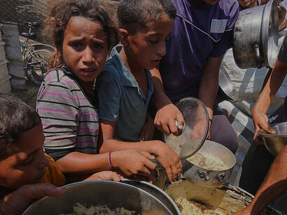 Palestinian families wait for food distributions provided by a charitable organization in Deir al-Balah, as humanitarian efforts continue to support vulnerable communities across Gaza