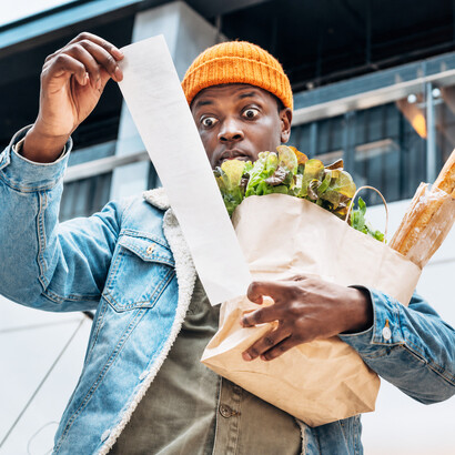 Concerned about expenses, an African American man reviews a receipt in a shopping mall amid ongoing economic challenge