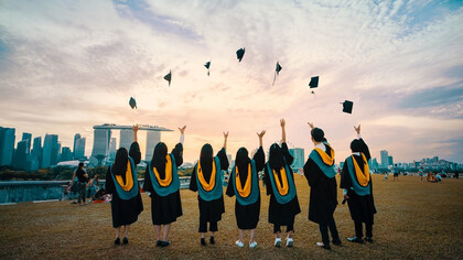 People throwing graduation hats on air