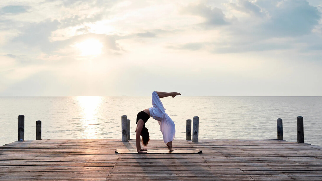 Mujer practicando yoga cerca del mar
