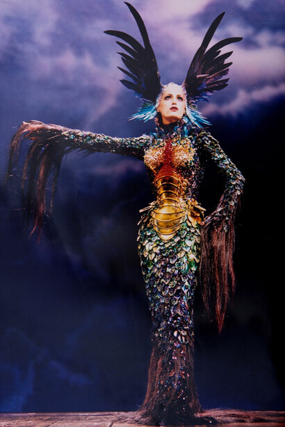 Alan Strutt, Yasmin Le Bon On Stage at the London Palladium, London, 1997; Evening Standard, October 31, 1997. Ensemble: Thierry Mugler, Chimera collection, haute couture fall/winter 1997-1998. Long sheath gown with scale-look body, feathers and horsehair embroidered with rhinestones, articulated golden bodice created in collaboration with Jean‑Jacques Urcun and Mr. Pearl. Photo © Alan Strutt.