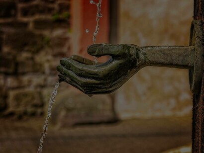 A metallic hand water fountain artistically pouring water into those hands