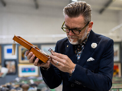 Antique clock specialist inspecting a timepiece in a traditional workshop