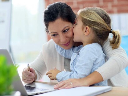Una mujer trabajando con su hija en brazos