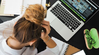 Woman with her hands on her head at her work desk