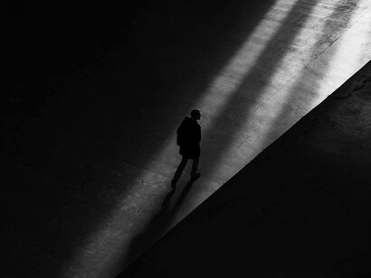 Persona in penombra cammina da sola verso l'uscita di un edificio