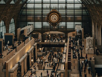 Visitors moving beneath the famous clock in Musée d'Orsay, Paris, France, reflecting how every passing minute carries social and economic value