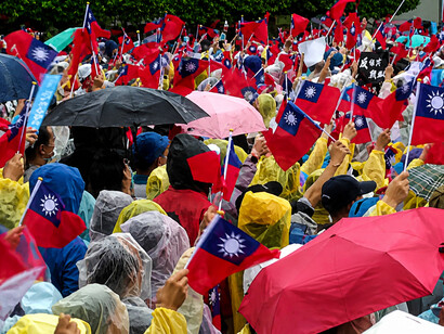 Crowds wave Taiwanese flags during a Kuomintang political rally, highlighting rising tensions between pro-China and pro-sovereignty factions within Taiwan’s political landscape