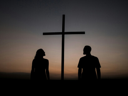 Una mujer y un hombre contemplan una sencilla cruz antes de que asome el sol. Mis manos los arropan cada noche, ocupan un lugar en mi corazón