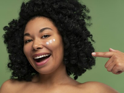 A woman preparing to moisturize her skin, representing the role of consistent barrier care in supporting a youthful appearance