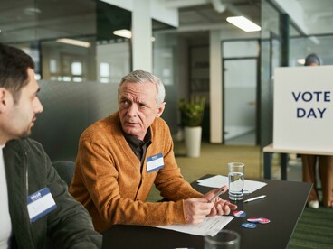 A man in a brown sweater waits outside a polling place while people vote on election day