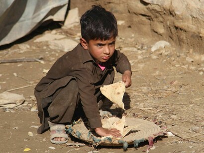 A small child grabbing food from the streets, homeless. The economic crisis and poverty in Pakistan at the current moment