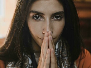 A brunette woman kneeling in a church, praying quietl