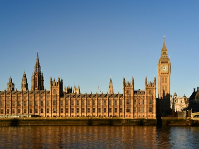 The Palace of Westminster in London, England, stands beside the River Thames, representing the foundation of parliamentary democracy