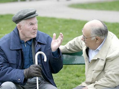 Dos ancianos dialogan en el banco de un parque