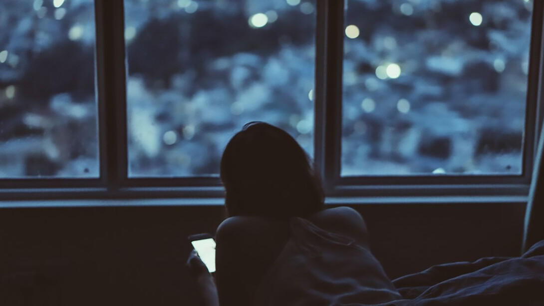 A woman in dark, looking at her phone