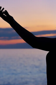 Silhouette of a woman stretching her hands to the sky, believing and wishing