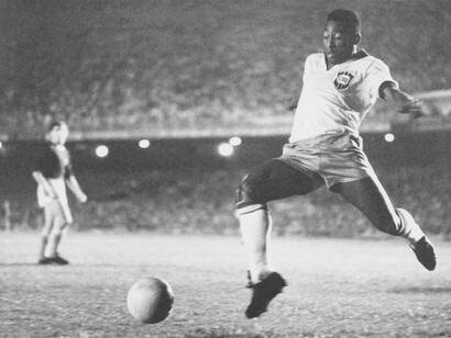 Young Pelé, Edson Arantes do Nascimento, on the soccer field, kicking a ball, while playing a game