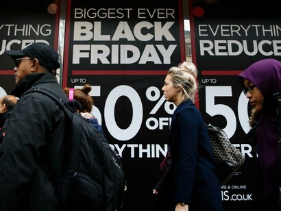 Viandantes ante anuncios de los descuentos por el "black Friday"