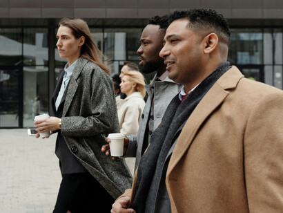 Coworkers take a coffee break and walk together, representing a diverse workplace team