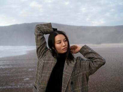 A woman stands alone on the beach, wrapped in a sense of quiet nostalgia
