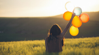 Woman holding balloons in a field