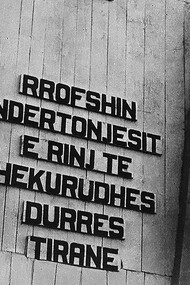 A clear symbol of Enver Hoxha’s personality cult: behind him and his closest allies stands a massive stone plaque bearing the coat of arms of communist Albania at the top, along with portraits of Hoxha and Stalin. Throughout his rule, Hoxha remained a staunch Stalinist
