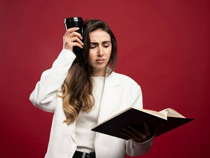 A reporter holding a cup and analyzing her notes, focused on her work
