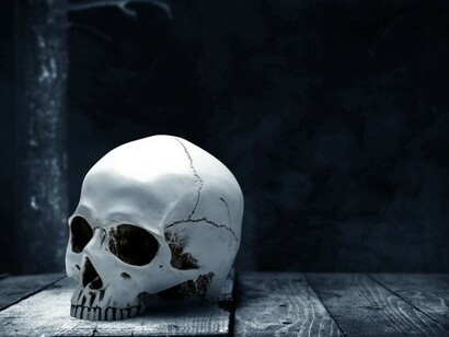 A human skull resting on a wooden table against a dark background