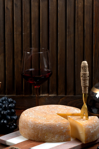 Round cheddar cheese served with grapes and wine, a classic pairing