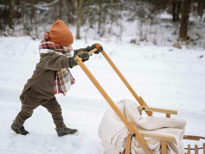 A child is pushing a sled in his pursuit to be helpful 