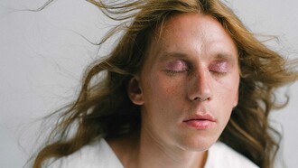 Modelo fecha os olhos para mostrar cores sintilantes em maquiagem nas pálpebras