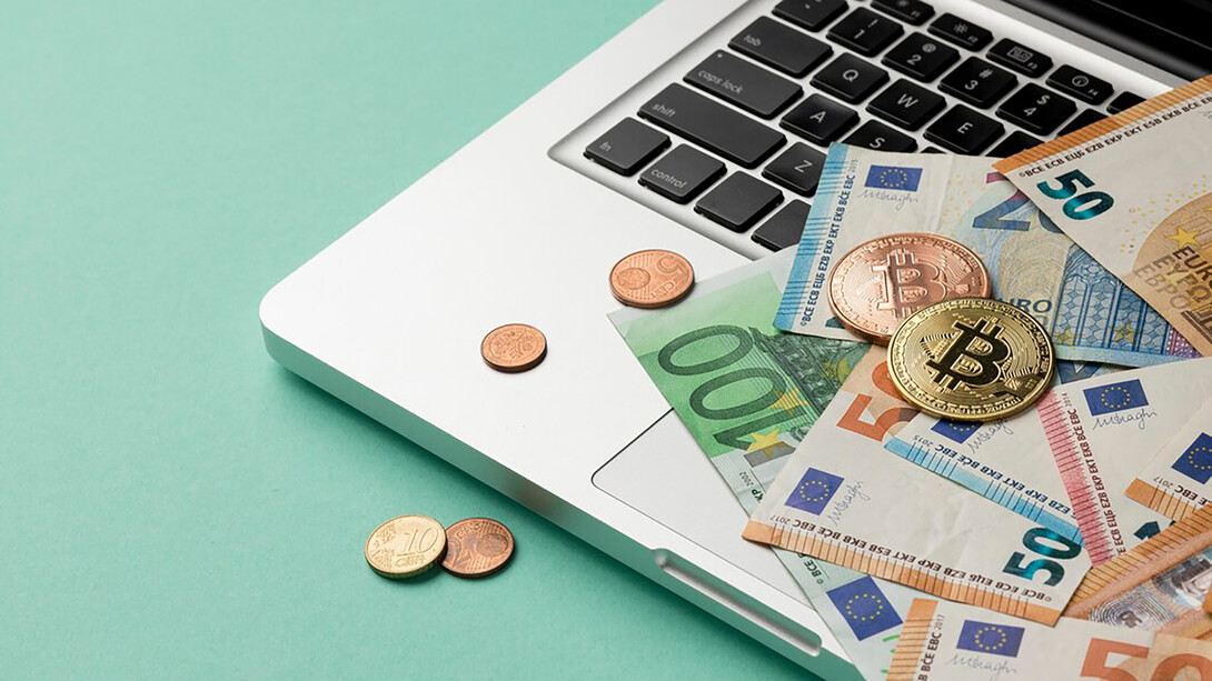 Euros and coins scattered on a computer, highlighting the transition to a digital euro