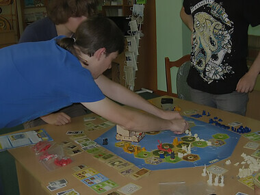 Discover the captivating world of Settlers of Catan as young boys delve into the strategic gameplay, bringing the board game to life with enthusiasm and skill