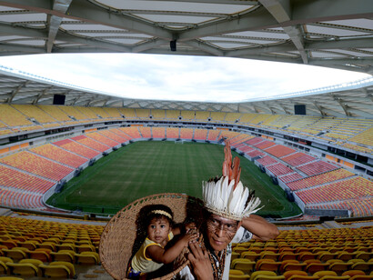 Imagem antológica. Cacique da etnia Satere-Mawé visita a Arena Amazônia com a família e carrega a pequena filha em um “paneiro”, elemento que inspirou a concepção do projeto arquitetônico da Arena. Fotografia Chico Batata 