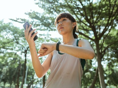 A fitness enthusiast reviewing health data on her wearable device, representing the rise of connected technologies that track daily activities and wellbeing