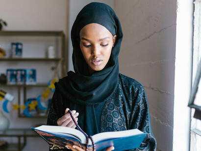 A woman in a hijab is holding the Quran