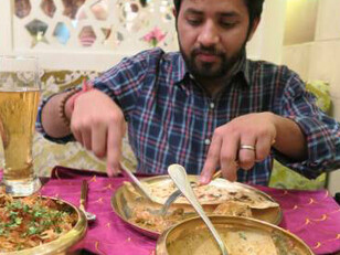 A Hindu man enjoying dinner at an Indian restaurant table, featuring a traditional Lucknowi biryani