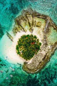 An aerial view of Guyam Island in Siargao, signifying the timeless allure of small islands surrounded by vast seas