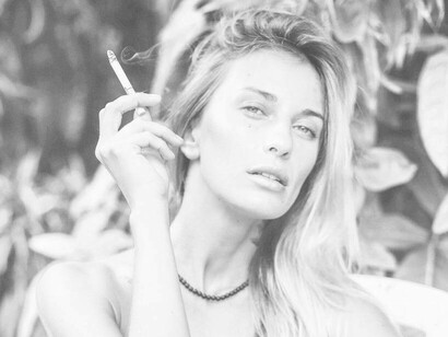 A woman looking in the distance with a cigarette in hand