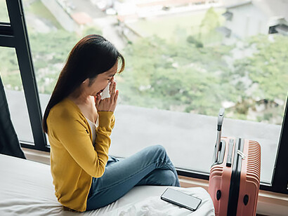 A woman cries on the floor next to her suitcase, suggesting a moment of departure and emotional distress