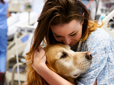 A therapy dog comforts a young female patient during a hospital visit, bringing warmth and emotional support