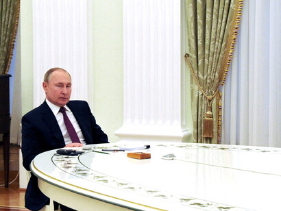 Vladimir Putin sentado à mesa de reuniões