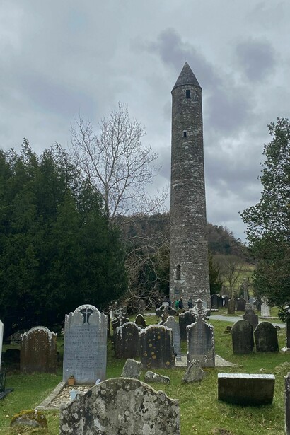 La famosa Torre Redonda de piedra domina el paisaje del antiguo cementerio monástico. Glendalough, Irlanda